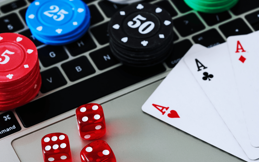 Laptop keyboard covered with poker chips, dice and playing cards